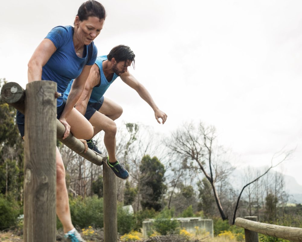 Couple,Jumping,Over,The,Hurdles,During,Obstacle,Course,In,Boot